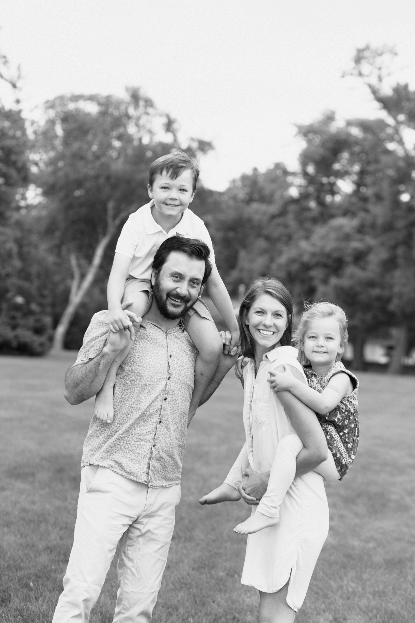Black and white family portrait showing playful interactions in an open field setting.