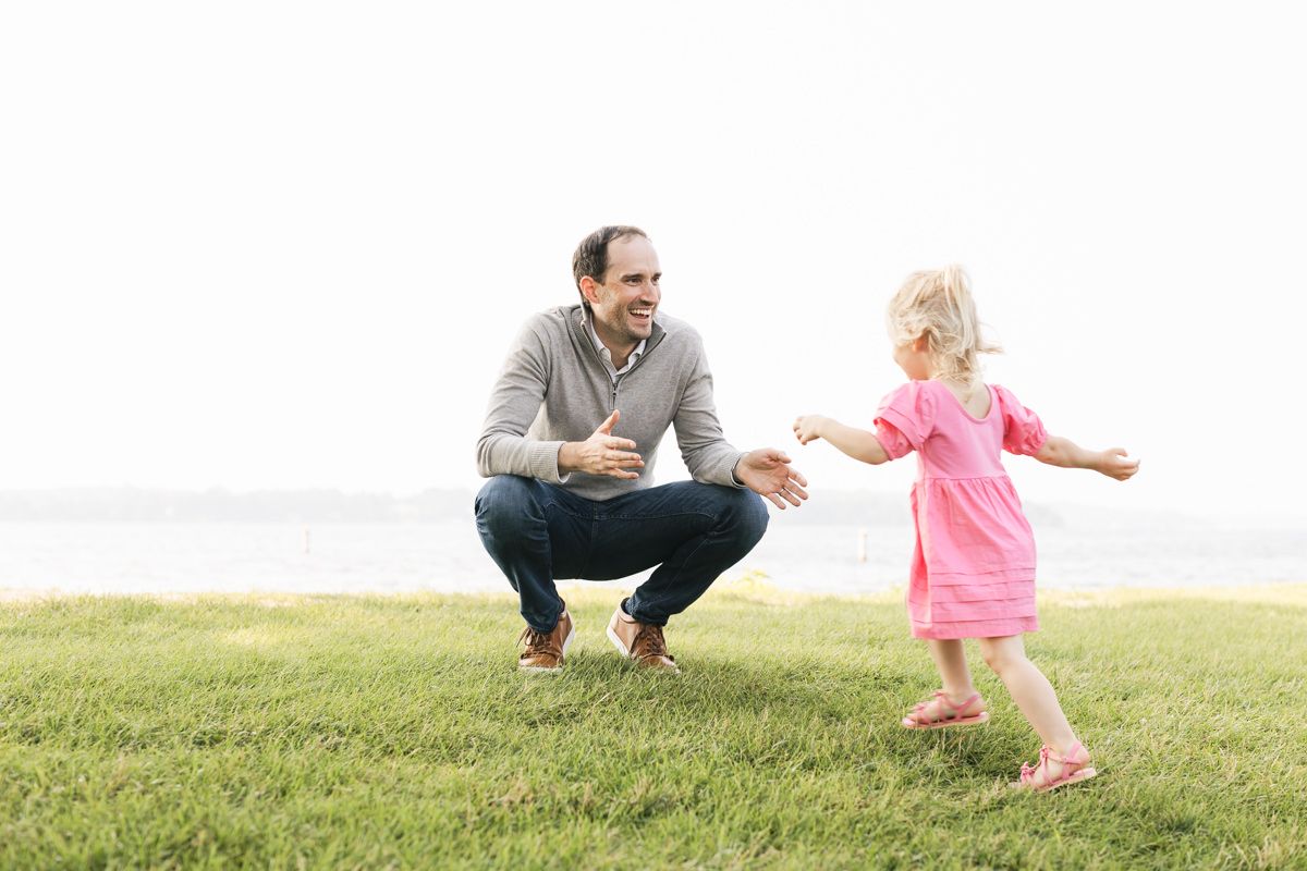 Parent and toddler playing together on grassy hill.