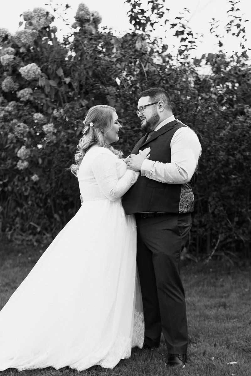 A couple in wedding attire dances together in a garden setting, captured in a series of black and white photos.