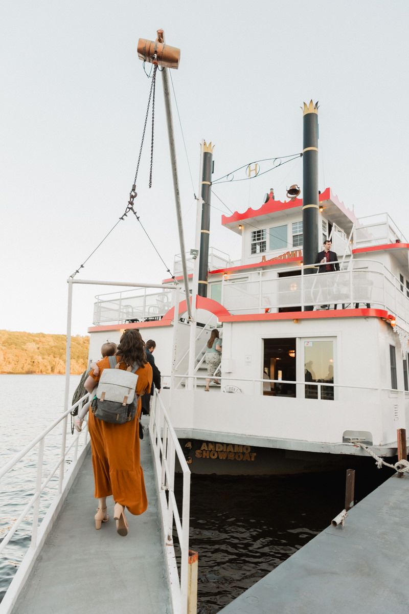 White riverboat with red trim docked on calm waters at sunset.