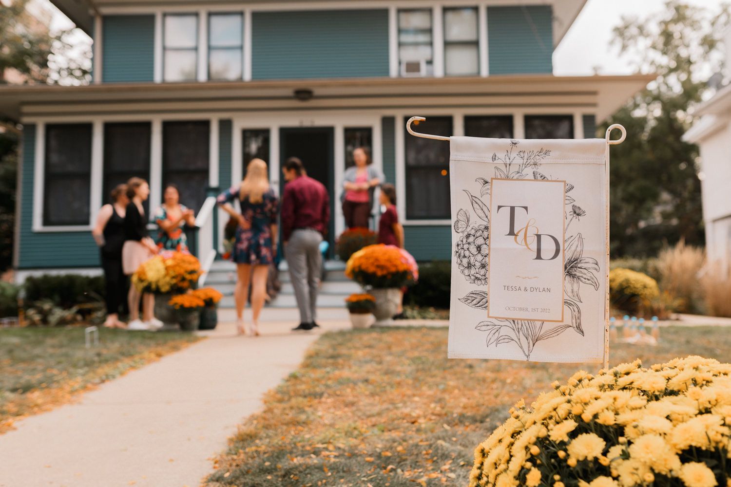 Wedding decor with yellow mums and white signs lining an outdoor walkway leading to a venue.