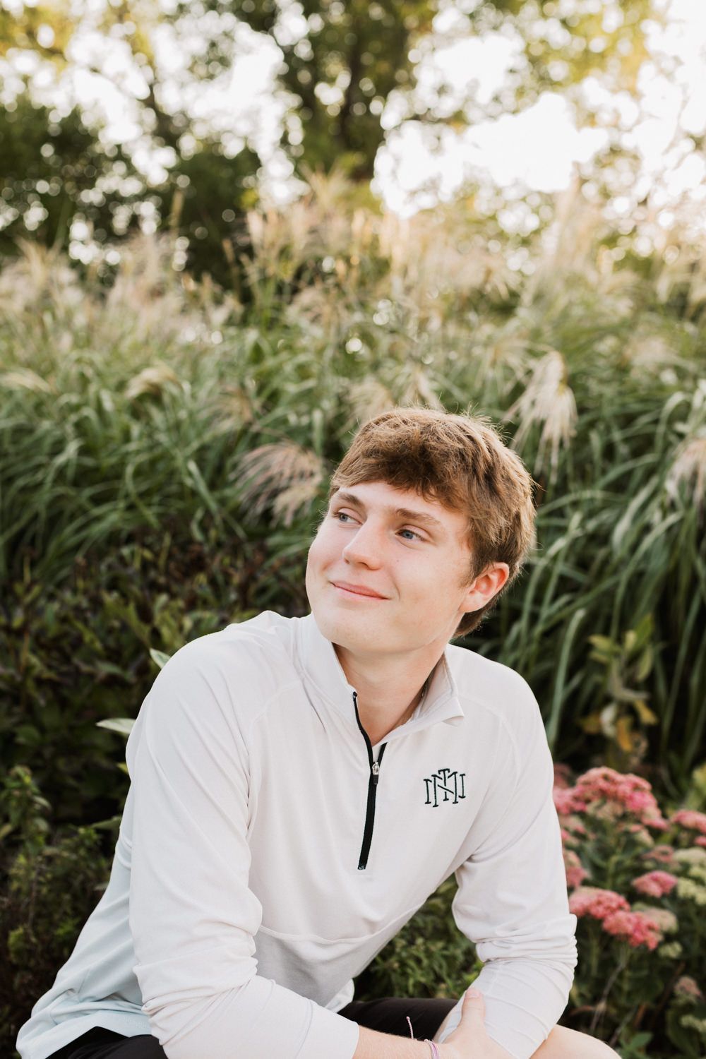 Portrait series against lush garden background with greenery and pink flowers.