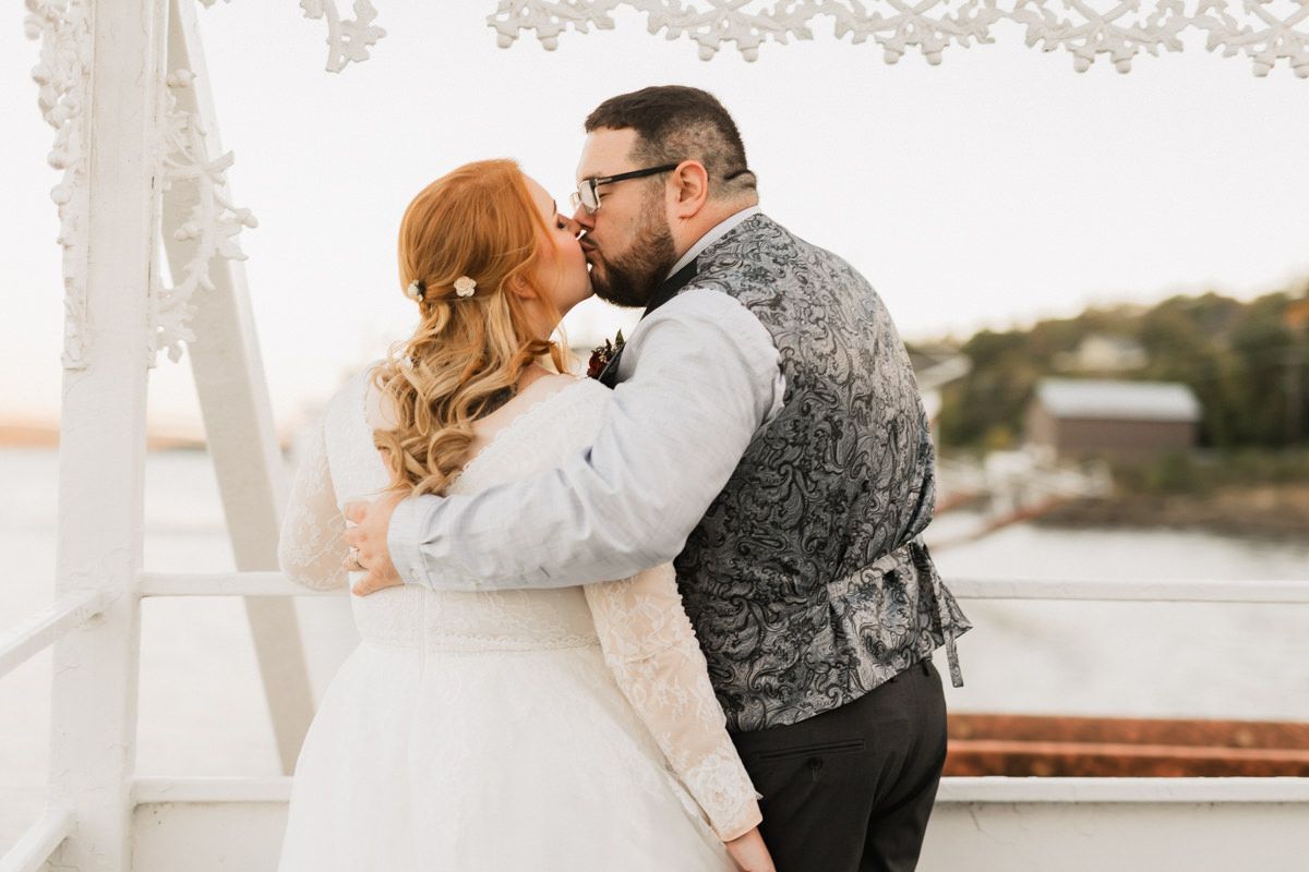 Romantic wedding moment captured on a white decorated deck with soft lighting.