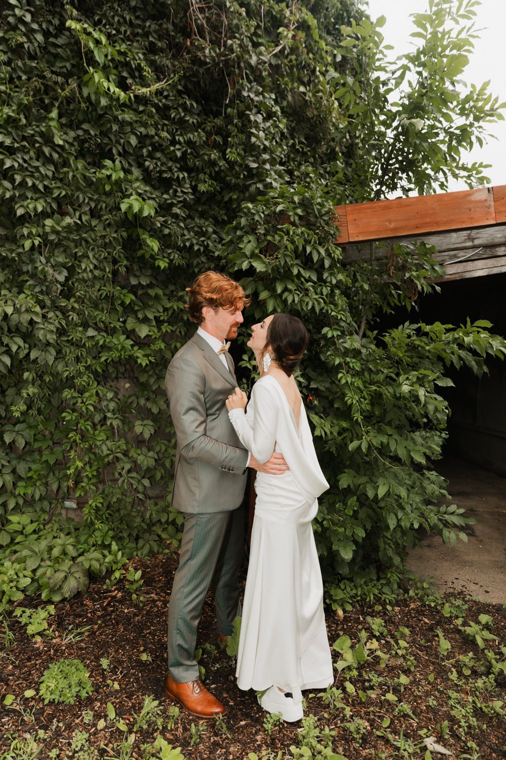 Couple shares intimate moment against lush green foliage backdrop.