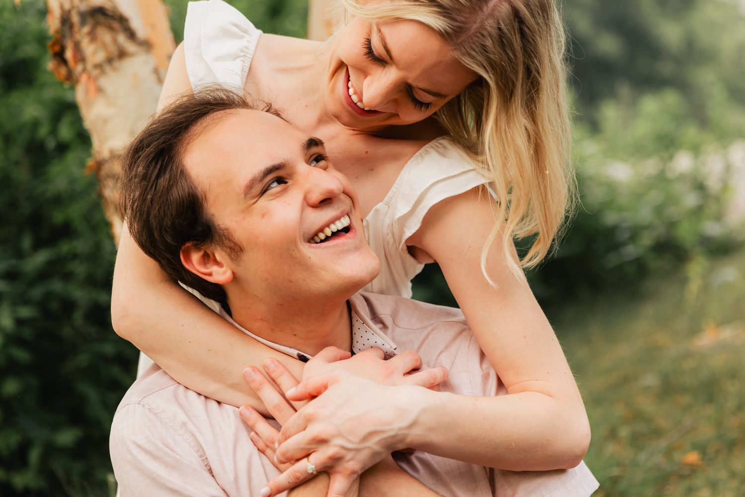 Joyful couple sharing playful moment outdoors in light summer attire.