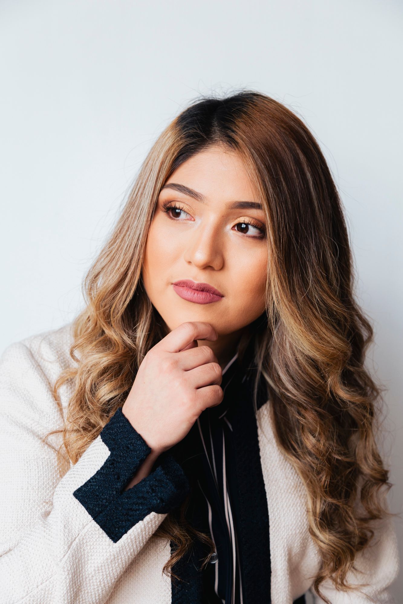 Professional headshot of a person with ombre hair in a white blazer against a light background.