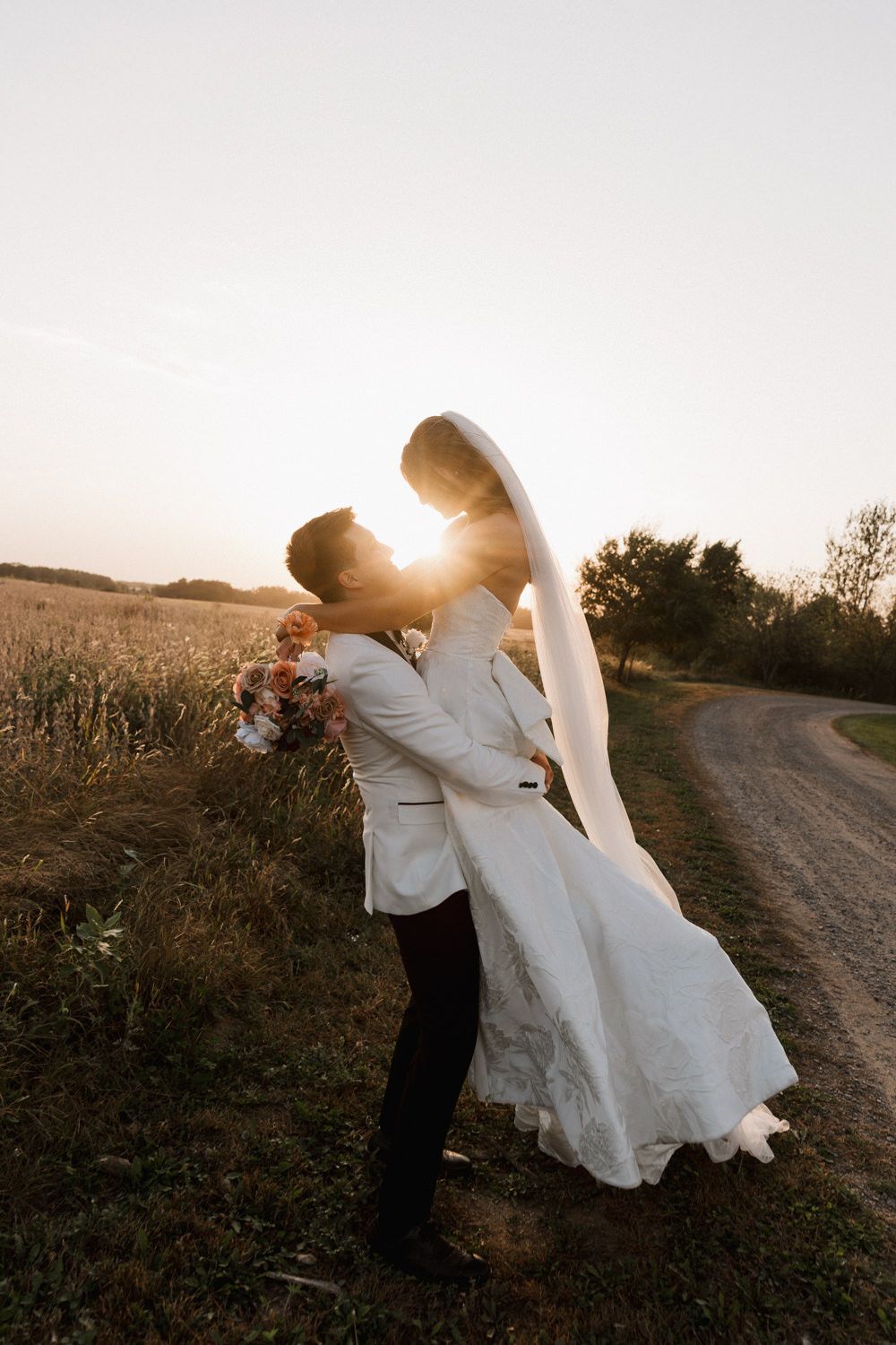 Dramatic sunset wedding photos with couple dancing in rural setting.