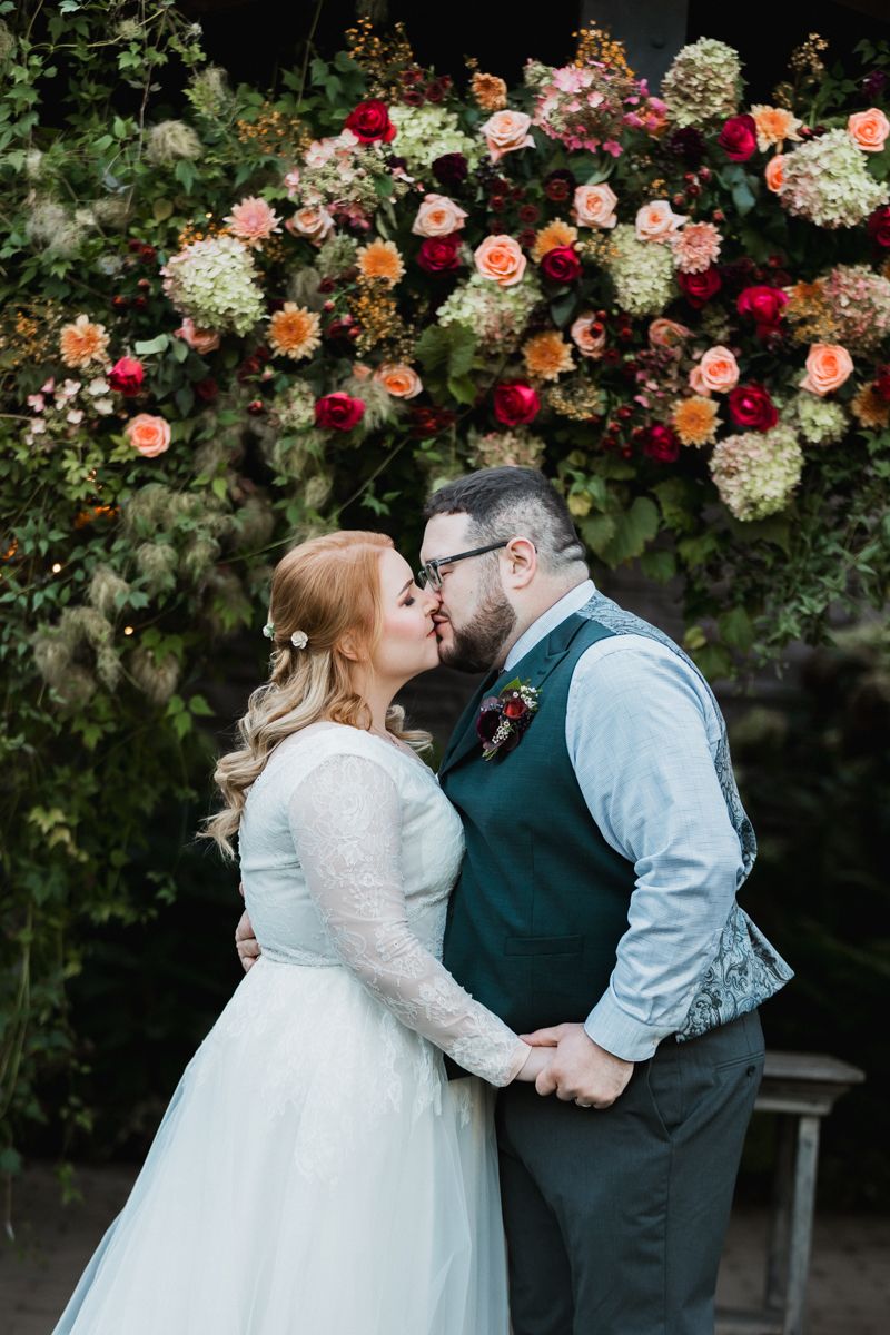 A tender wedding moment captured in front of a beautiful rose garden backdrop.