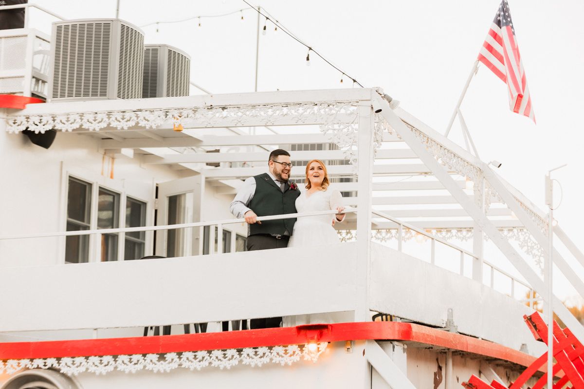 Vintage white riverboat with red trim and string lights at dusk.