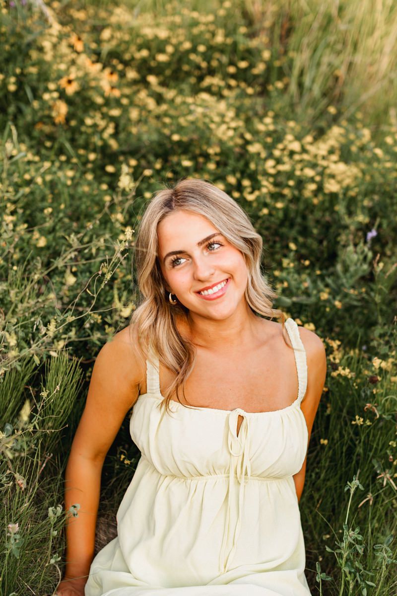 A summer portrait taken in a wildflower meadow showing a cream sundress against a natural green background.