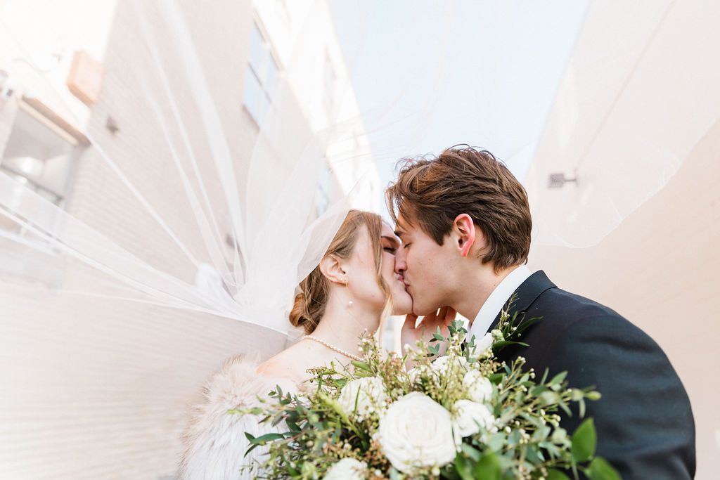 Romantic winter wedding portraits with an elegant couple and white floral bouquet.