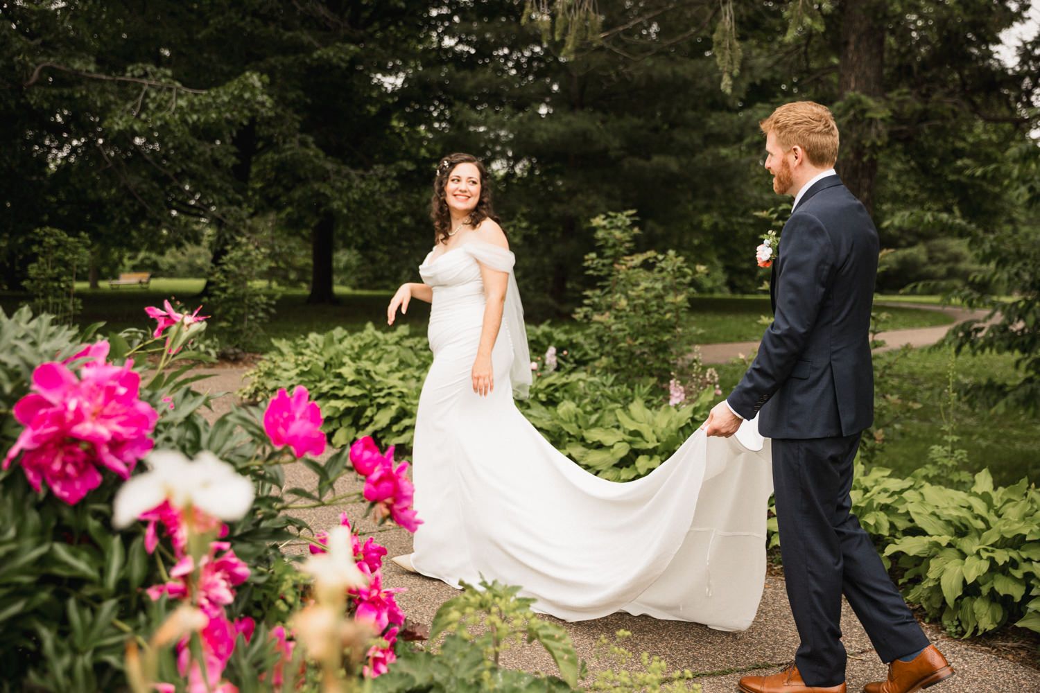 Elegant wedding photo in a garden with bright pink flowers in the foreground.