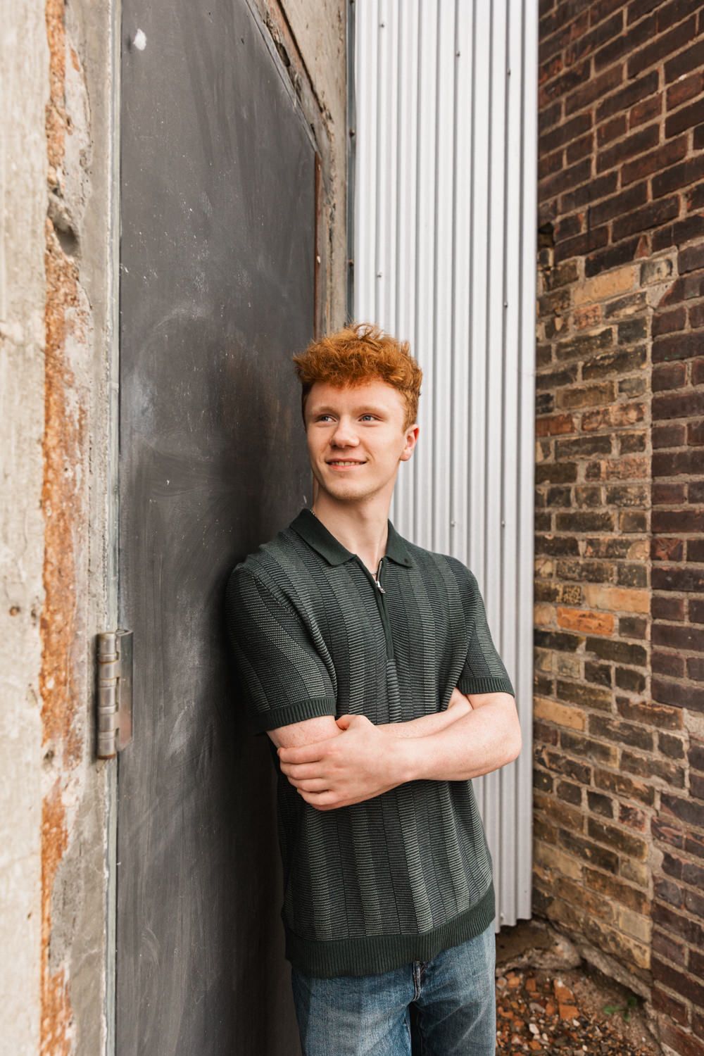 Person stands beside white column against exposed brick wall in industrial architectural setting.