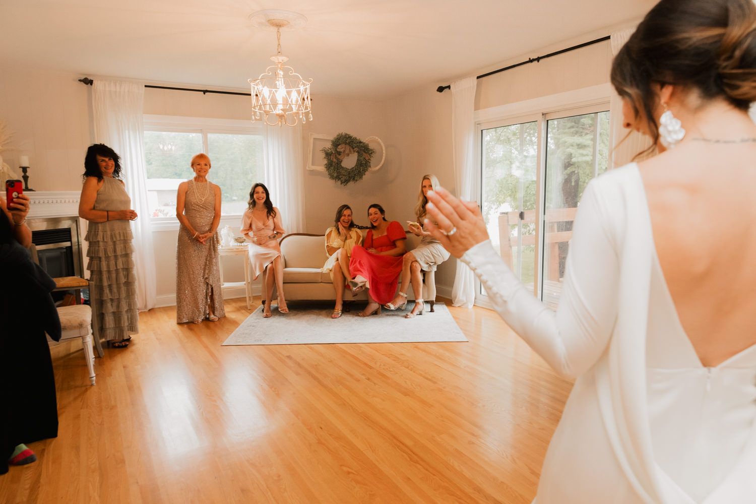 A series of wedding preparation photos showing a bridal gown being fitted in a bright, sunlit room with hardwood floors.