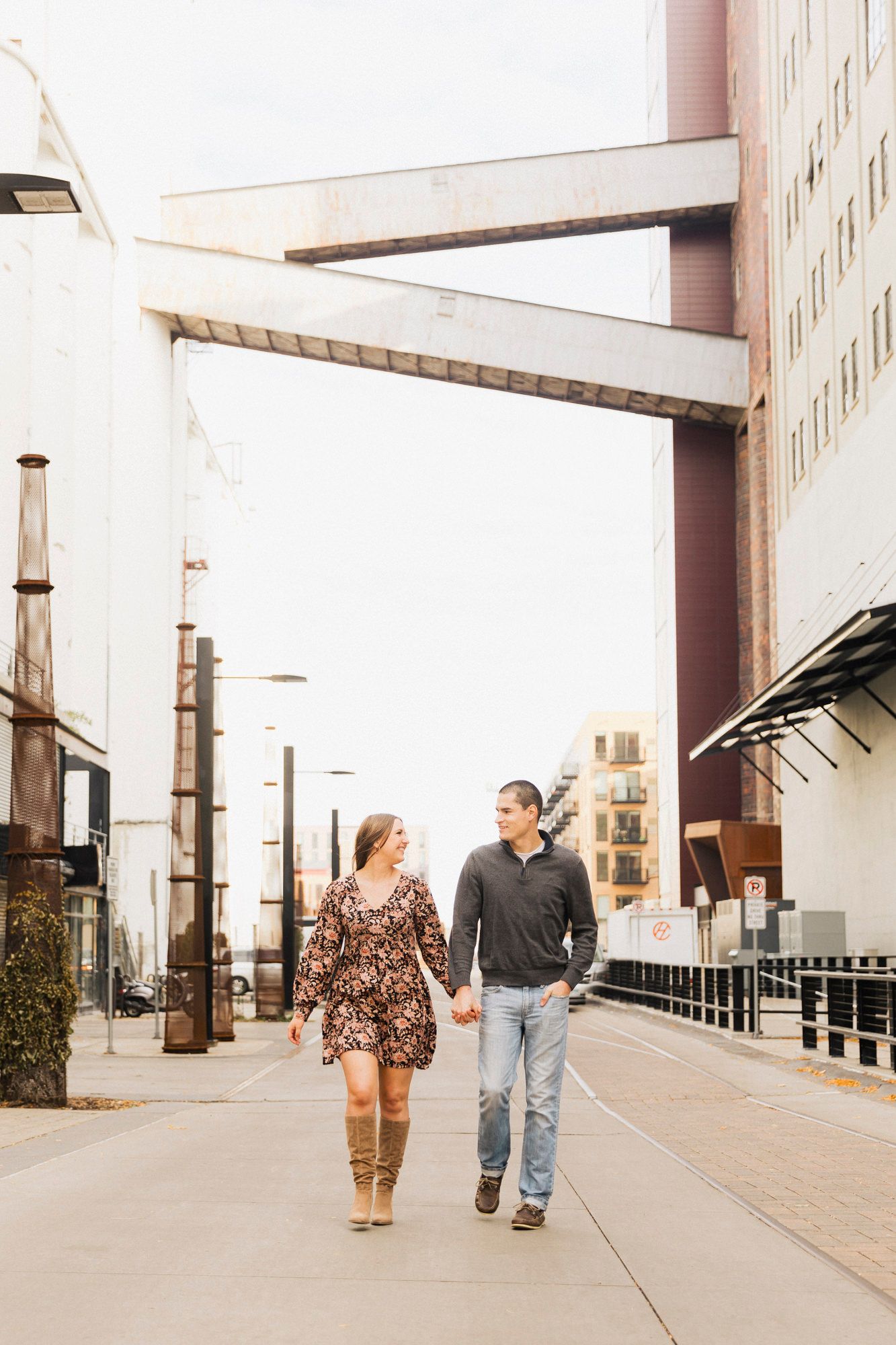Couple walking under urban architecture with industrial design elements.