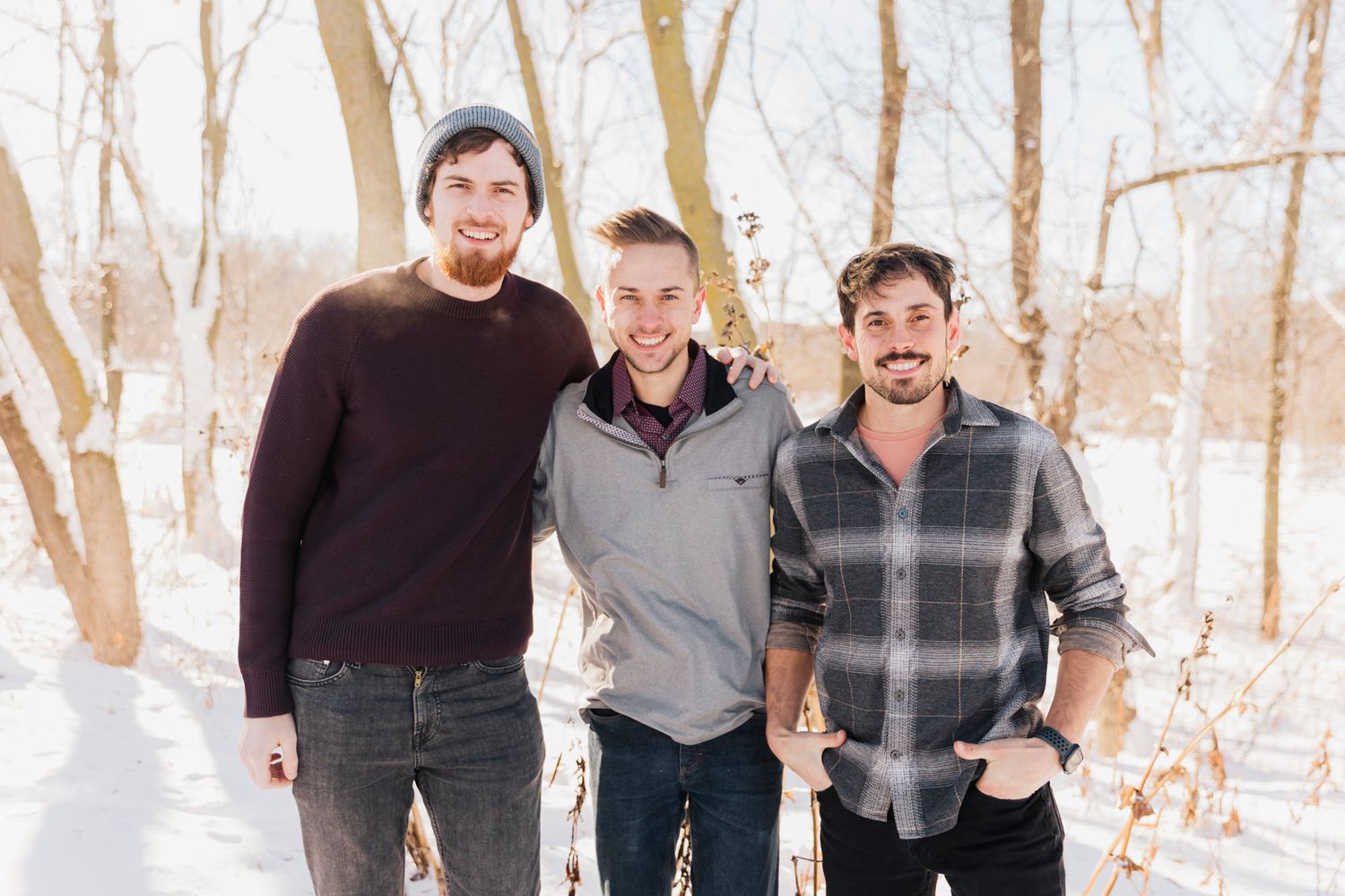 Winter family photo with group walking through snow-covered wooded landscape.