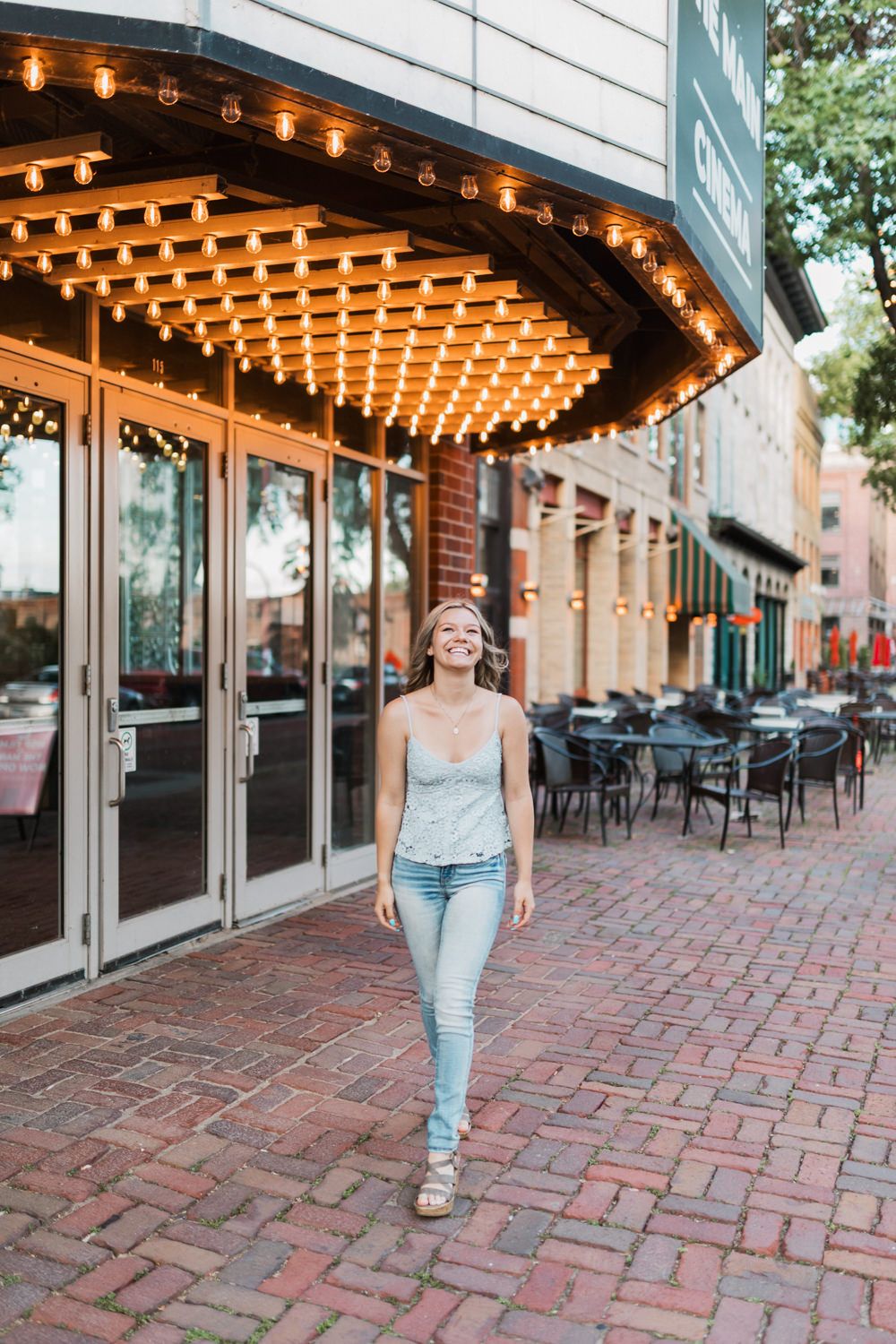 A series of photos showing someone walking on a brick sidewalk under string lights outside a storefront at dusk.