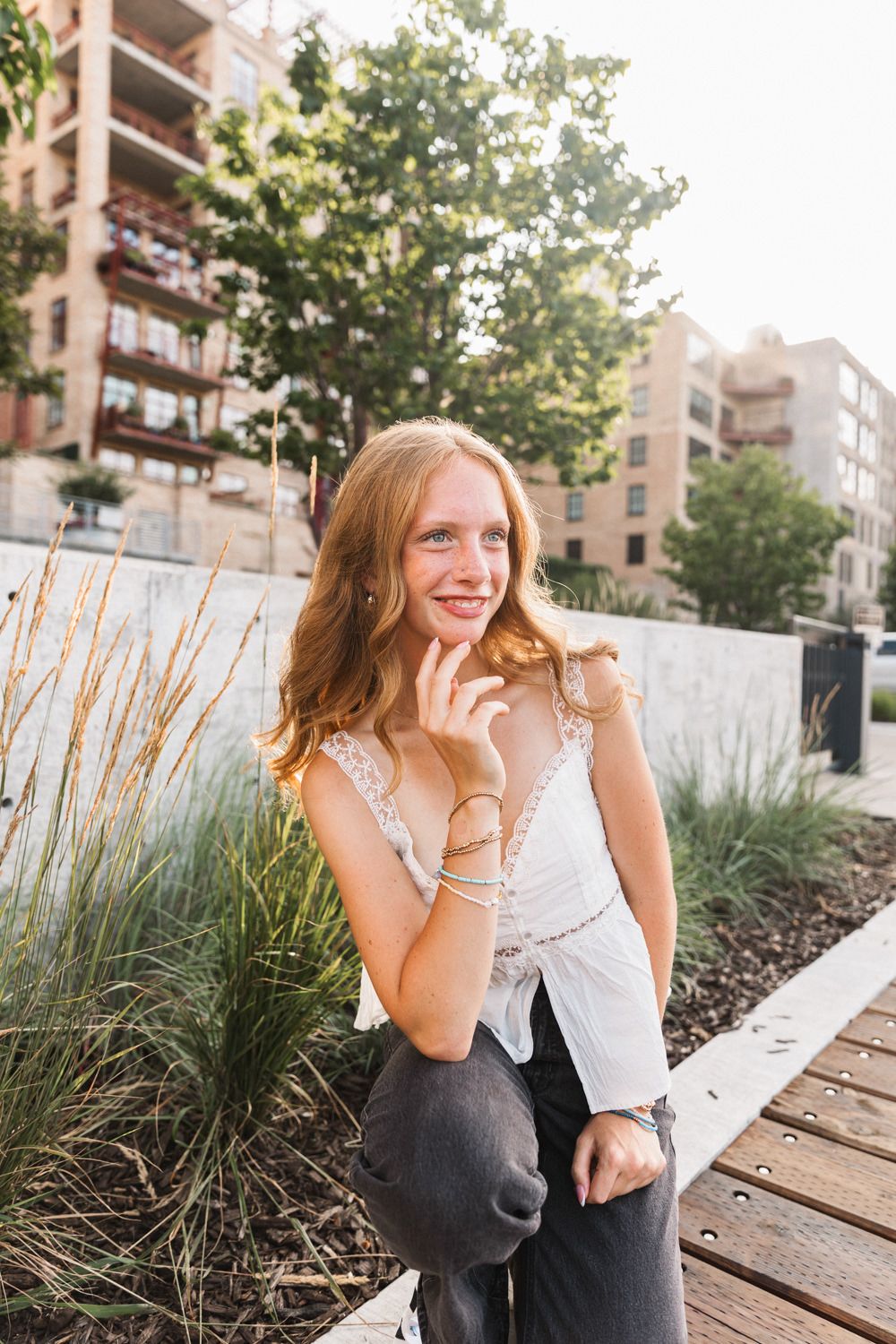 Outdoor portrait by ornamental grasses with apartment buildings in the background.