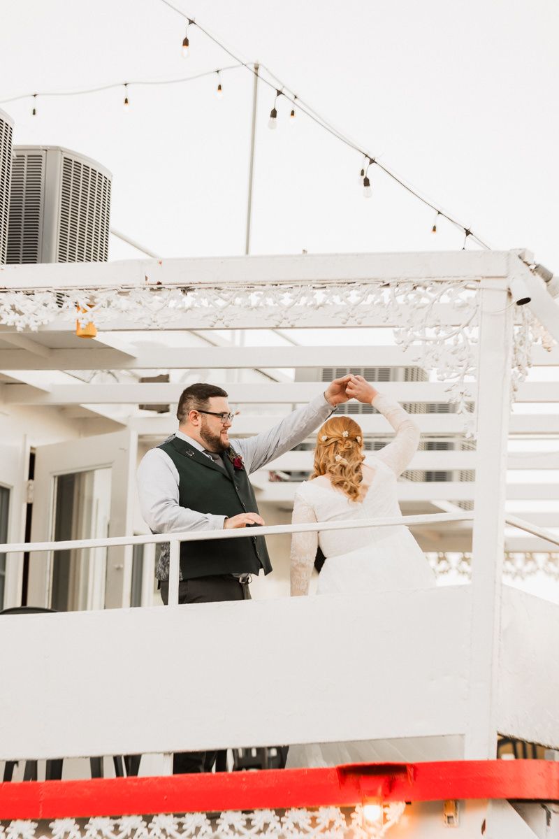 Couple dancing together on a bright white balcony or deck with modern architectural details.