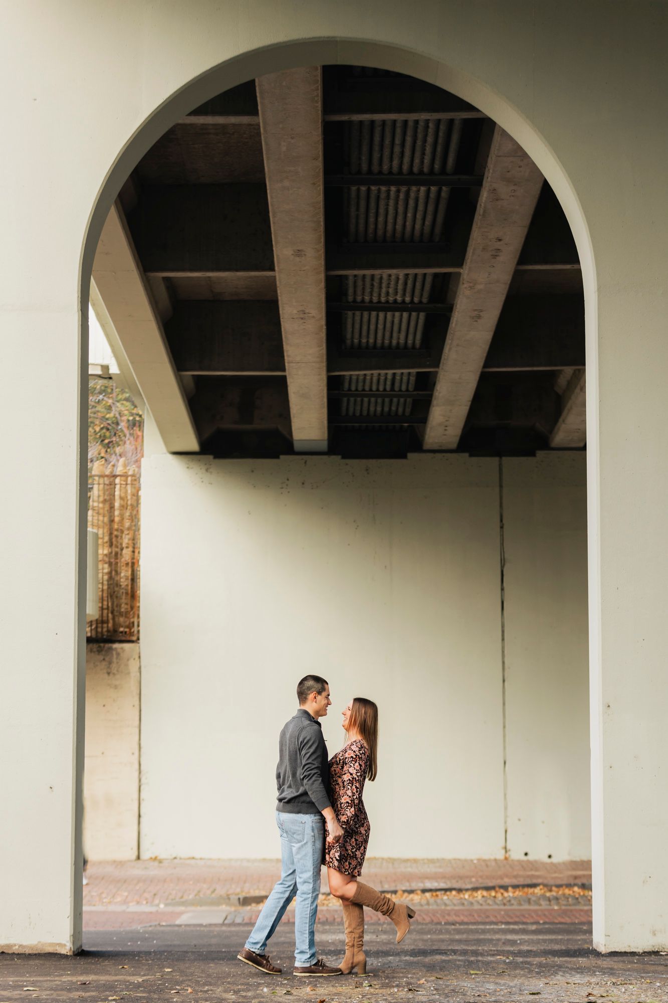 Couple standing beneath geometric archway in urban setting.