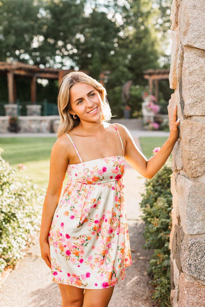 Summer portrait session against stone columns and garden features at sunset.