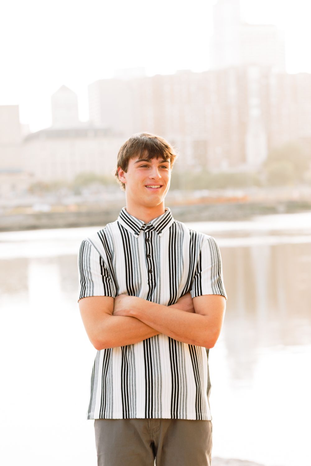 A figure wearing a striped shirt stands with arms crossed against a beige background.