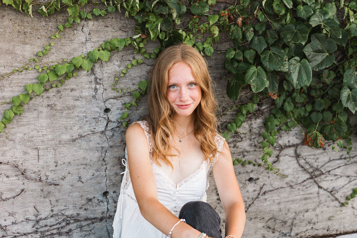 Summer portrait against a white wall with climbing ivy plants.