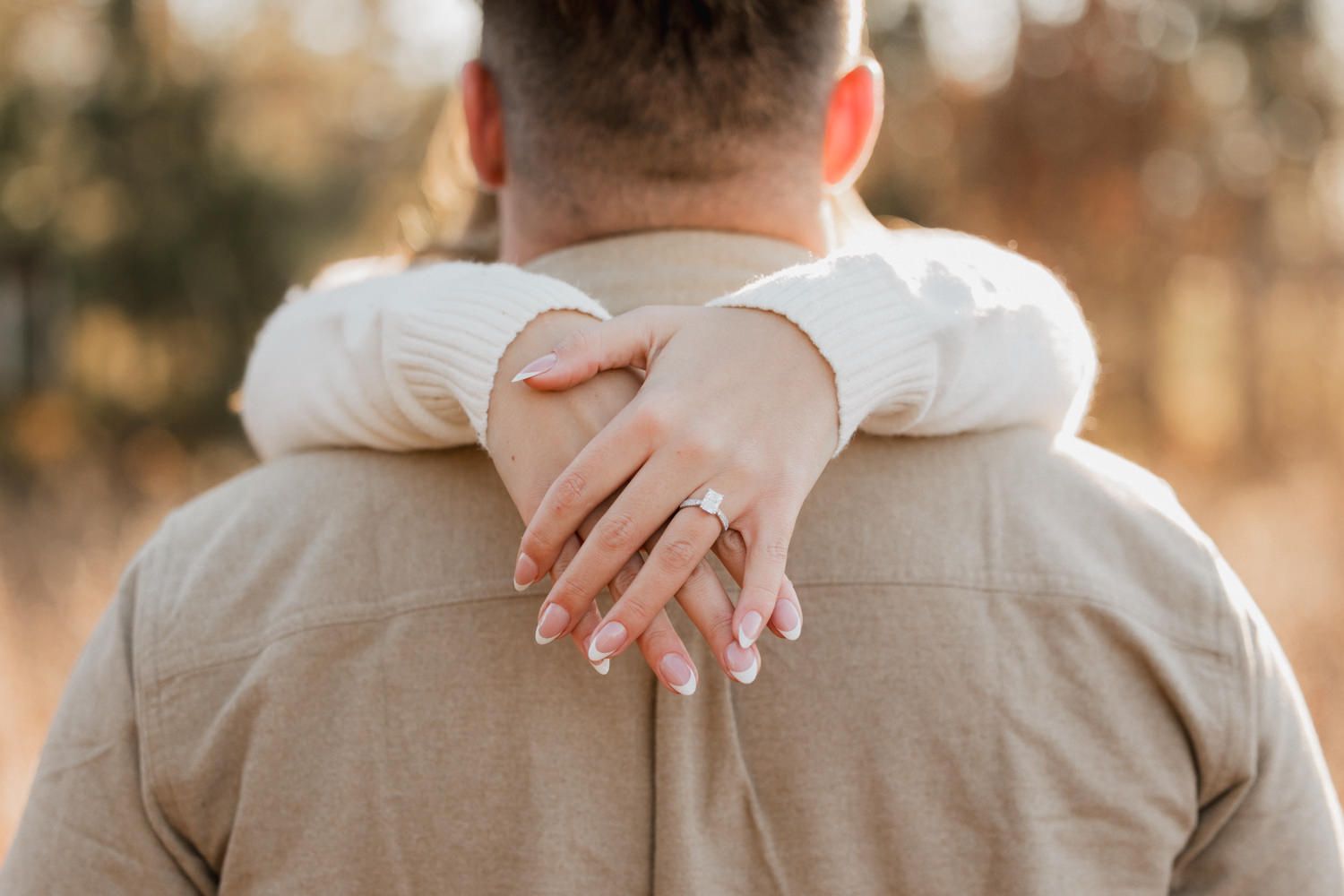 Close-up view of a couple's tender embrace in a serene outdoor setting with natural lighting.
