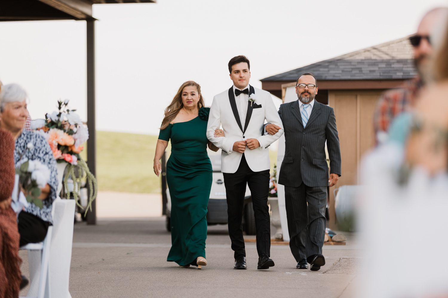 Wedding party walking together outside a building with bridesmaids in emerald green dresses.