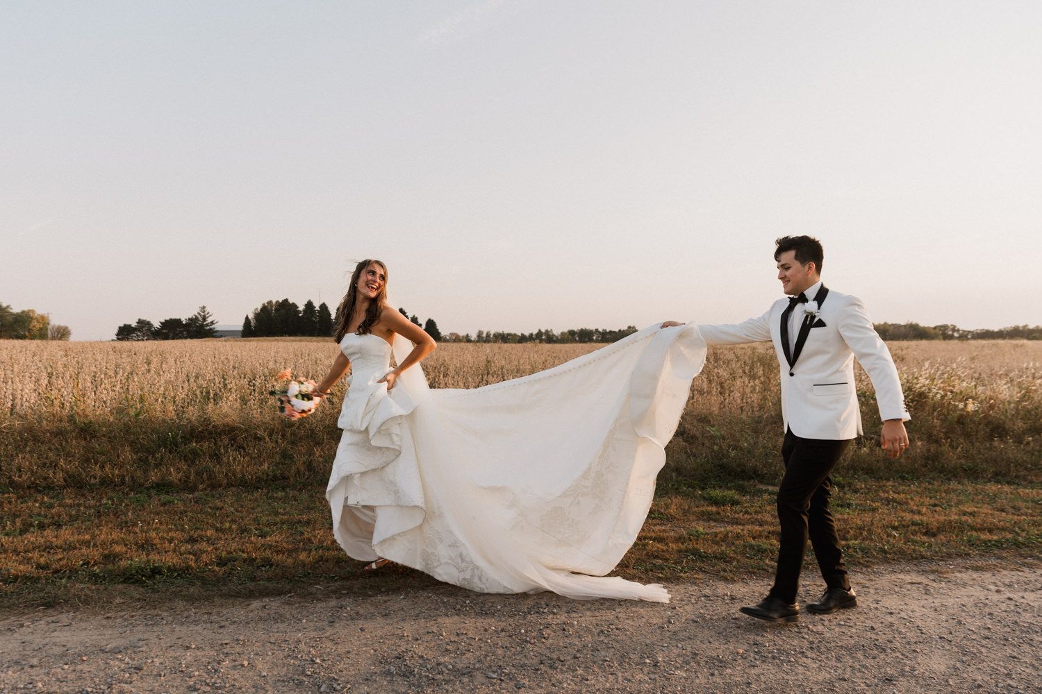 Wedding couple walks along a rural path during golden hour photography session.