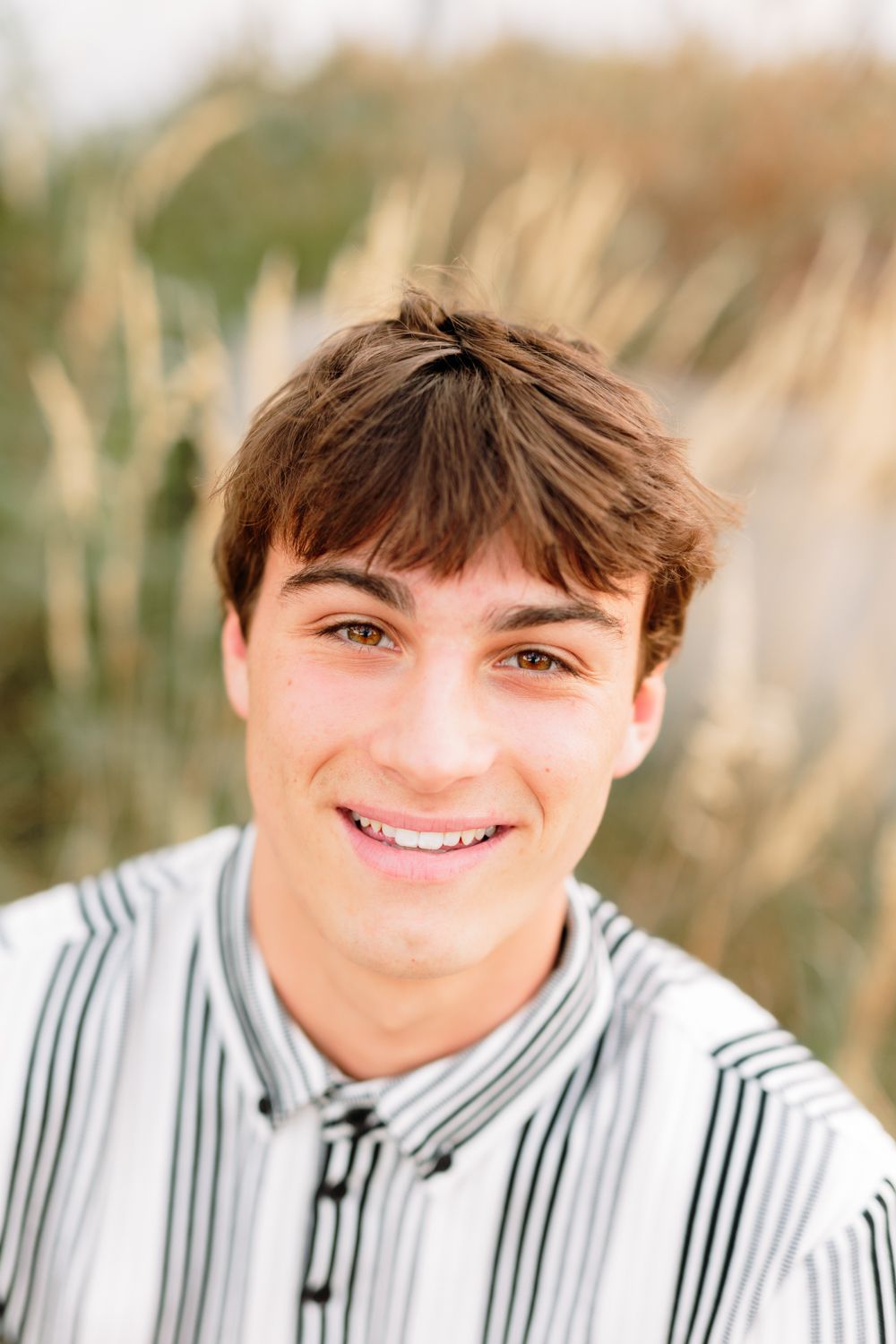 A portrait shot in natural light wearing a striped collared shirt.