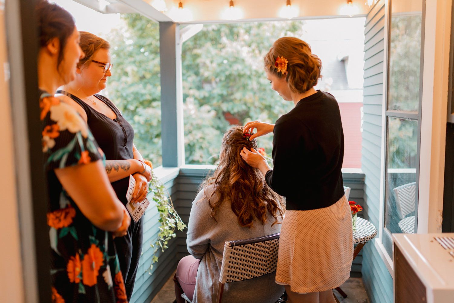 Wedding party members gather in a warmly lit indoor venue with decorative lighting and floral arrangements.