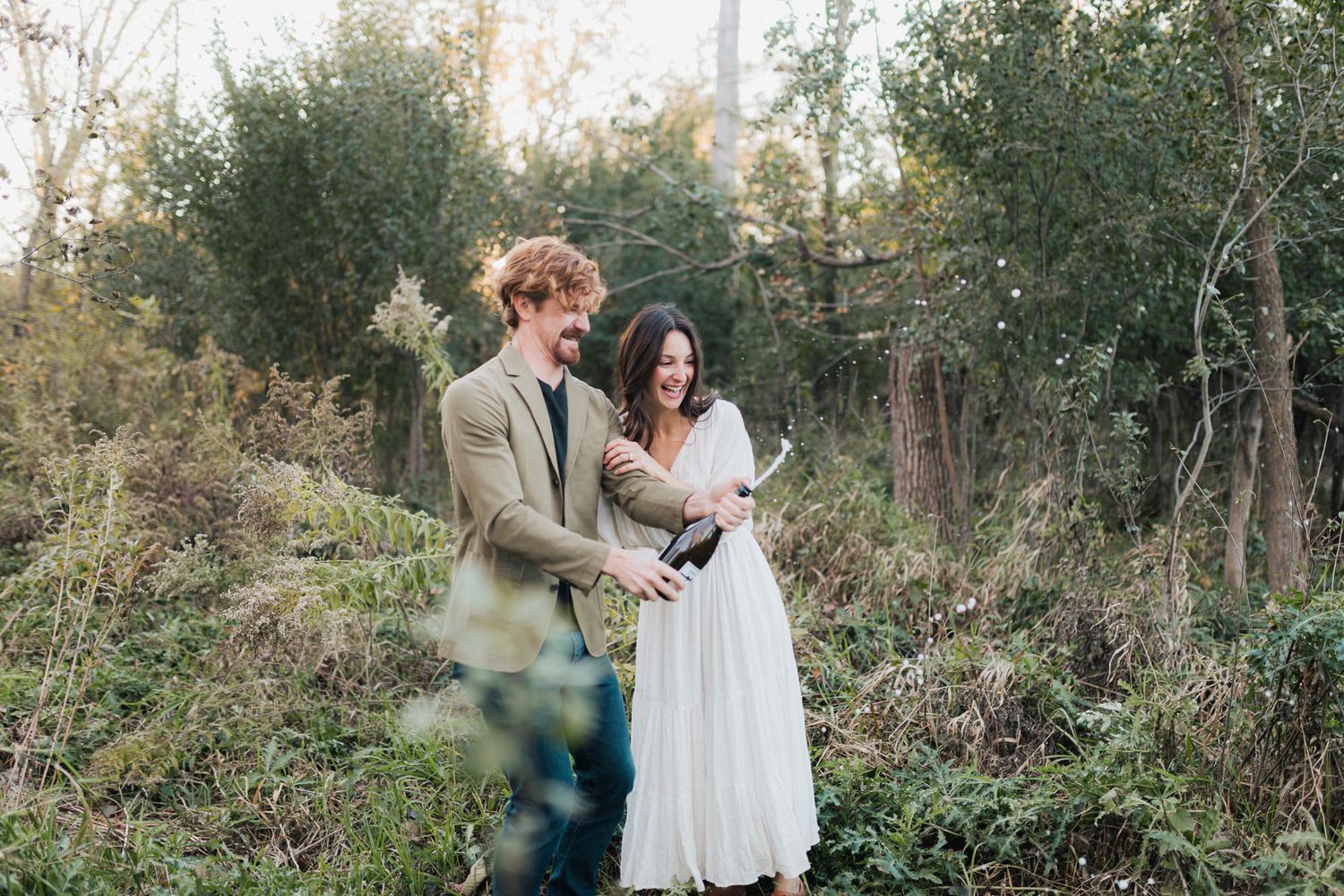 A couple shares a tender moment while standing among trees and foliage.