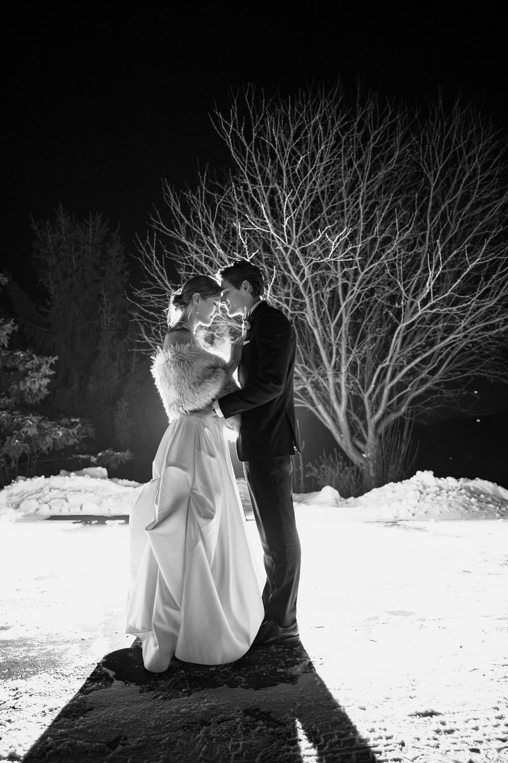 Black and white nighttime wedding photos with bare trees and snow creating dramatic silhouettes.