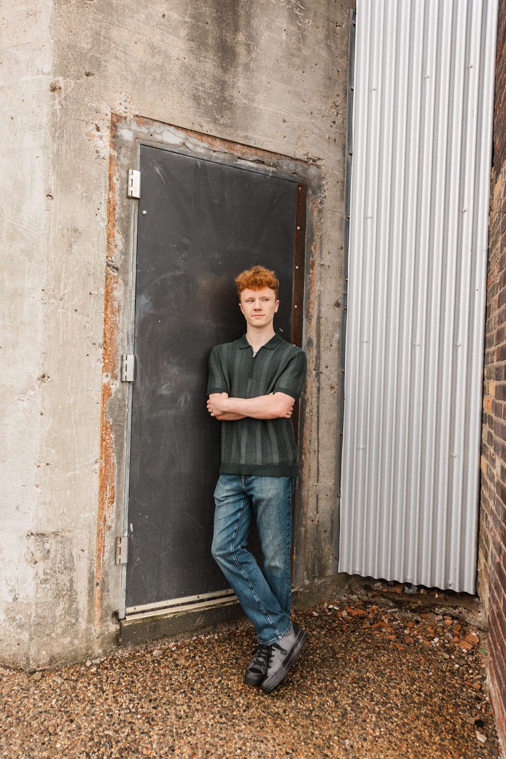 Fashion portrait series against industrial metal doors and concrete walls with gravel ground.