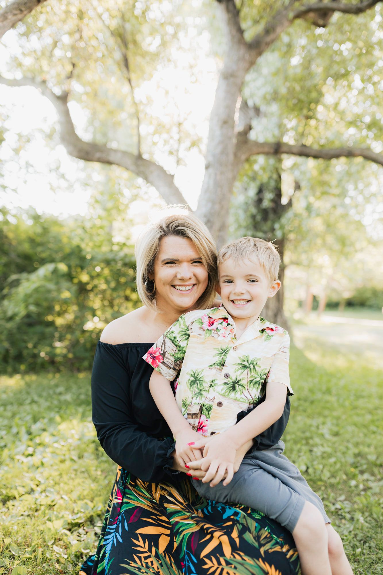 Sweet candid moment between parent and child sitting together in a grassy outdoor setting.