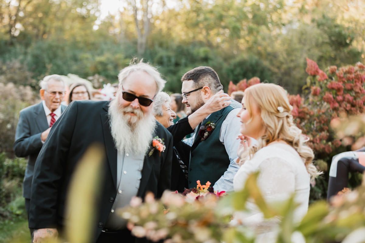 Joyful wedding celebration in a garden setting with guests mingling during golden hour.