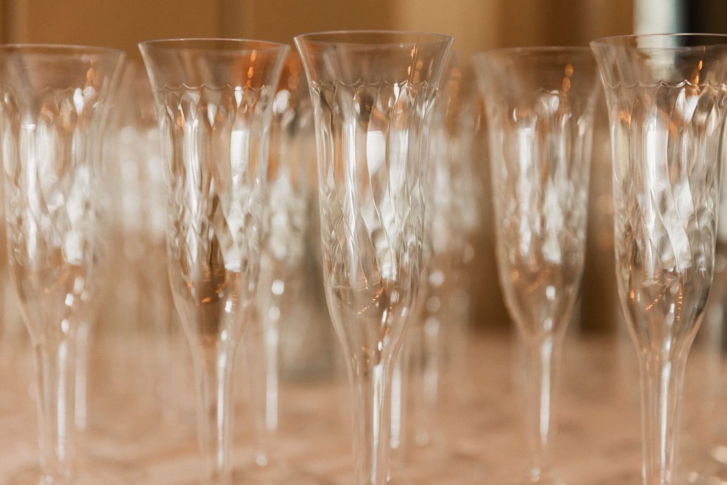 Rows of empty wine glasses lined up on a table at a formal event or restaurant setting.
