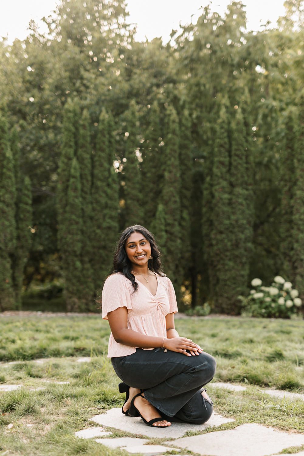 Candid outdoor photoshoot on grass with hedges in background.