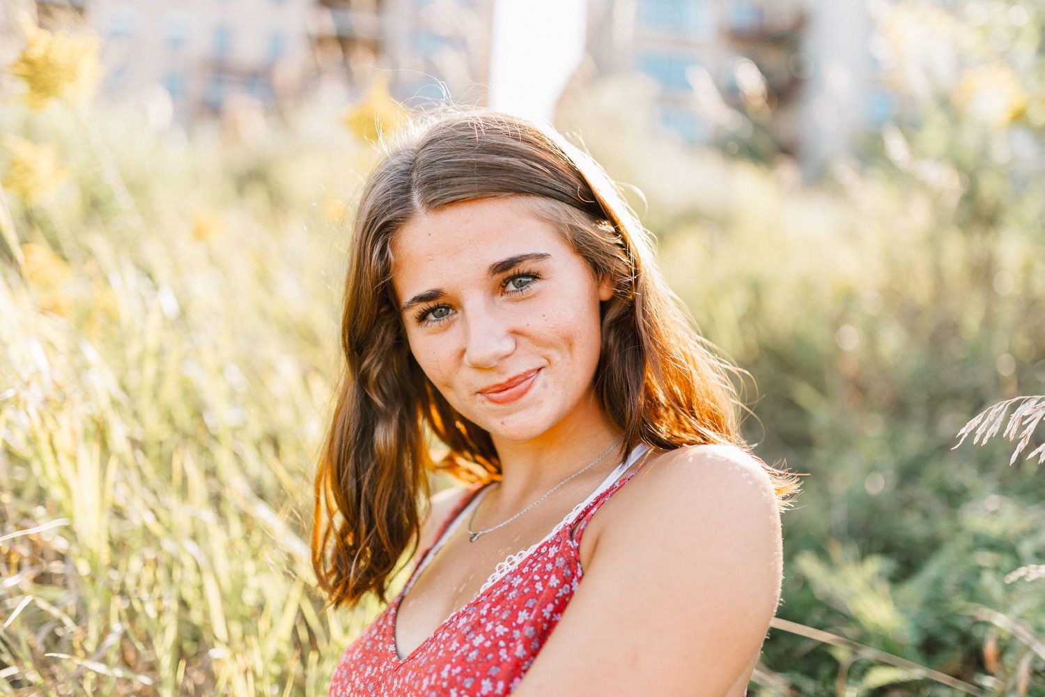 Summer portrait in a red polka dot dress among sunlit wildflowers.