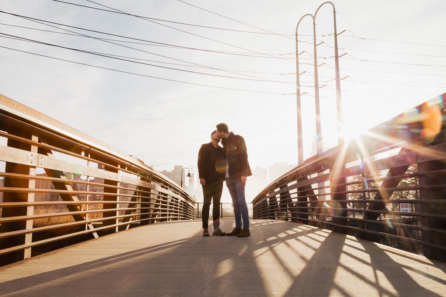 Silhouetted couple sharing romantic moment on wooden bridge at sunset.