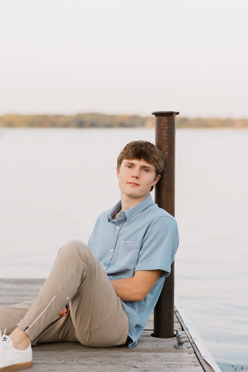 Casual portraits on waterfront dock with person in blue shirt relaxing against post.