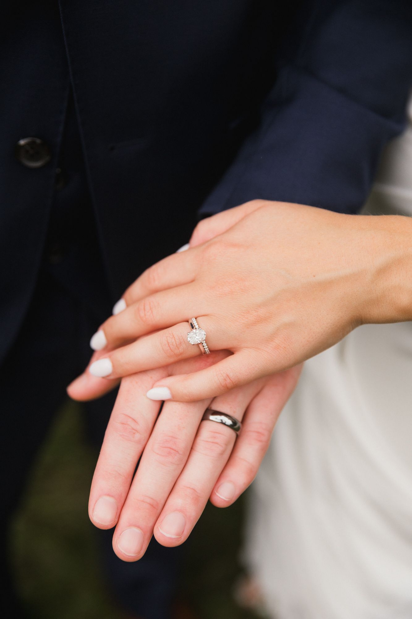 Newlyweds displaying wedding rings, bride wearing diamond engagement ring, groom with black band on ring fingers.