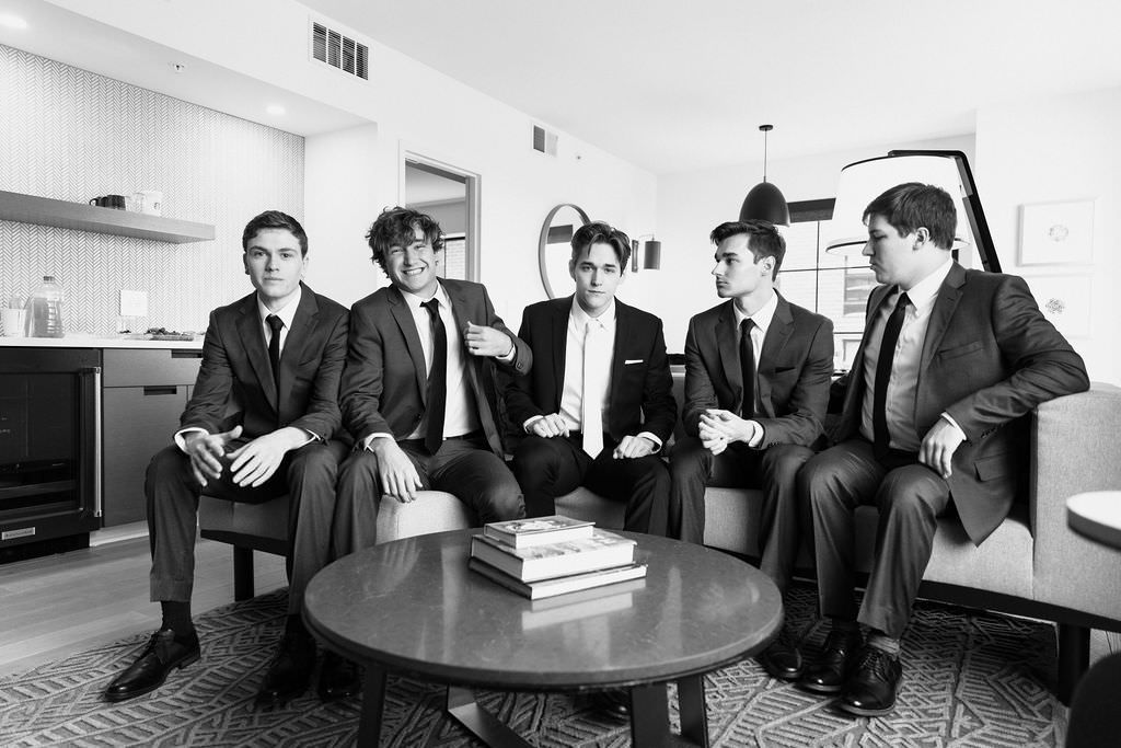 A black and white photo of a stylishly dressed group relaxing in a modern office lounge area.