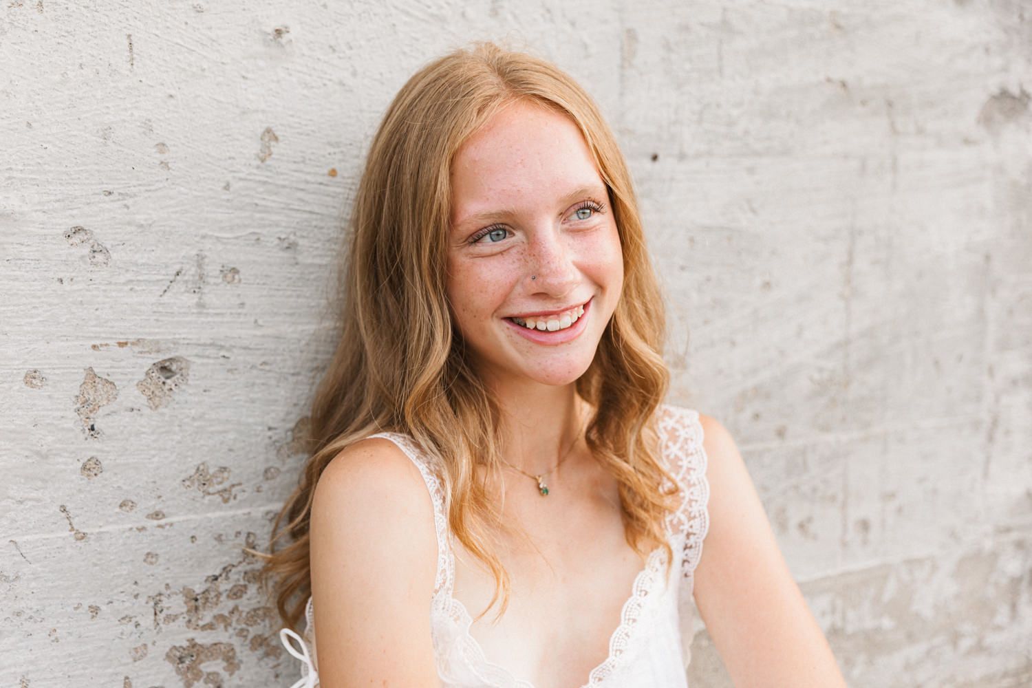 Four portraits against a gray wall showing a person with long strawberry blonde hair in a white top.