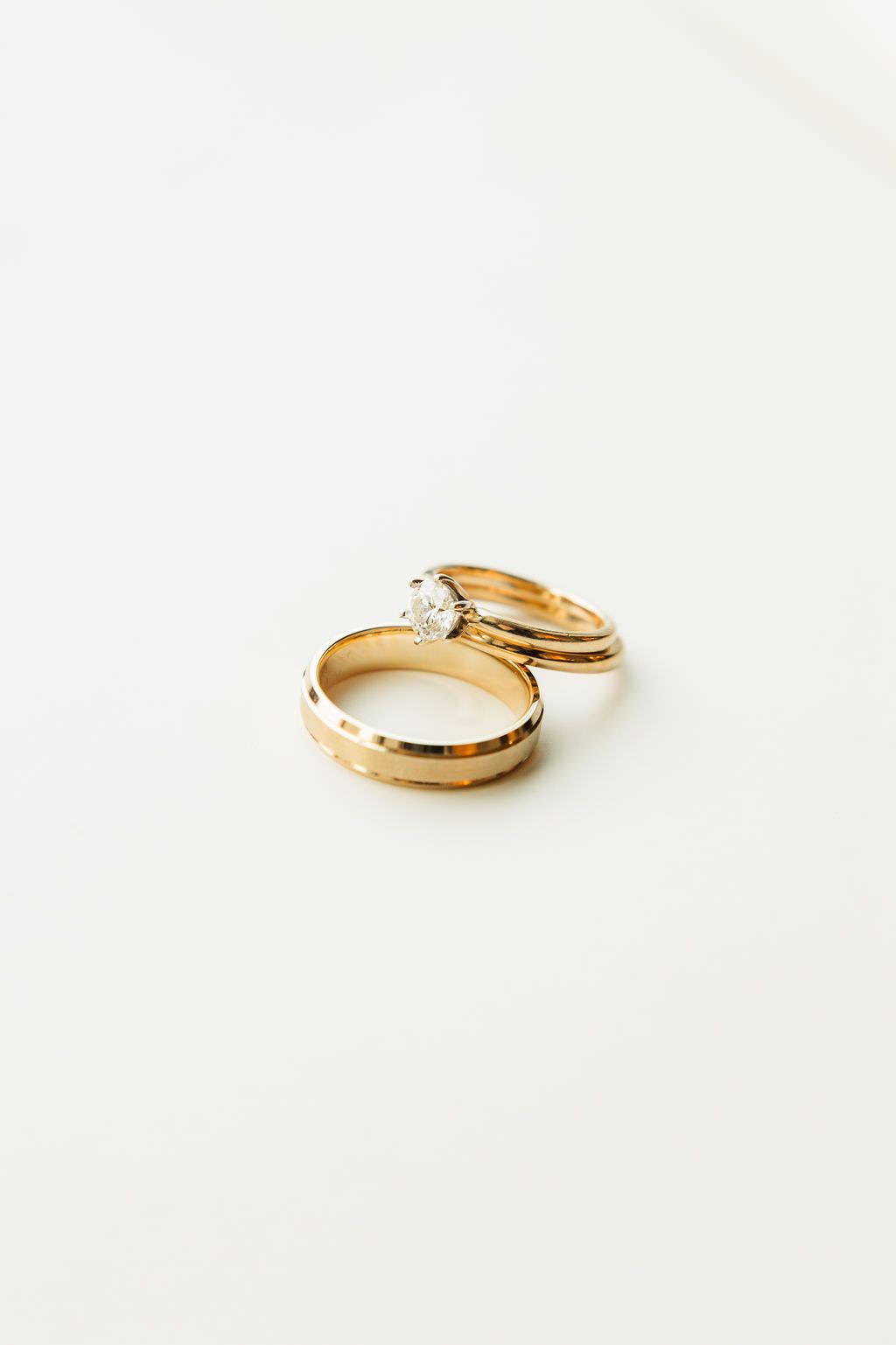 Gold wedding rings and diamond engagement ring displayed on white background.