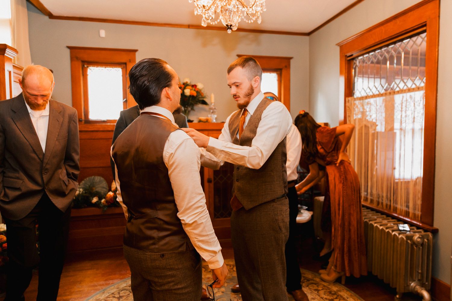 Wedding reception venue decorated with elegant chandeliers and wooden details in warm lighting.