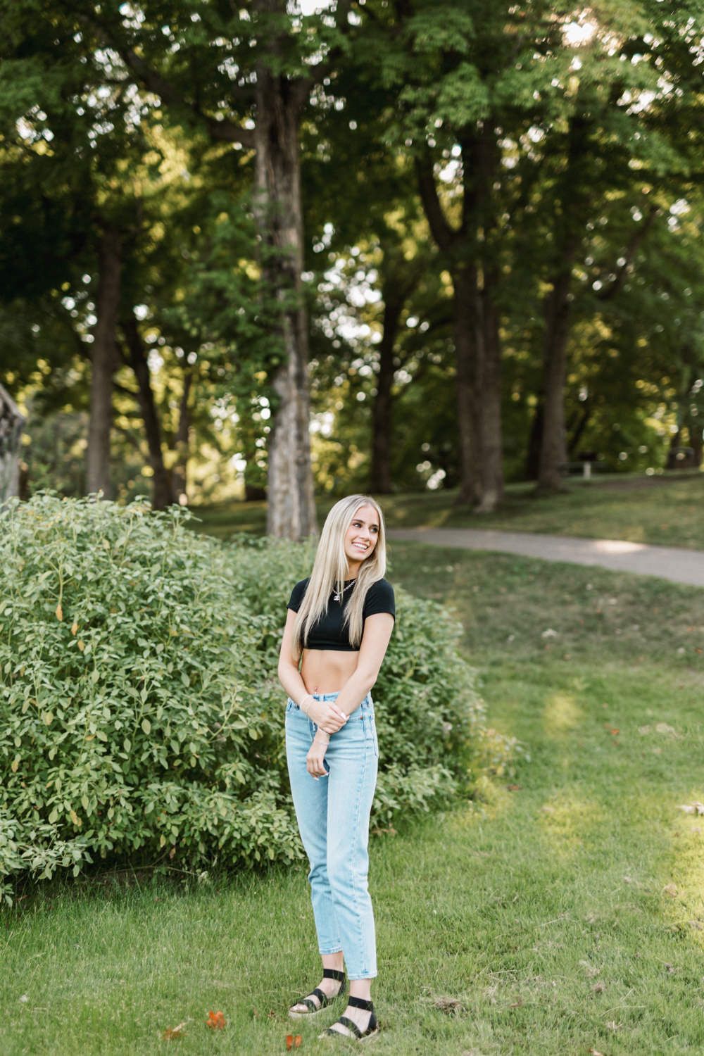 Casual lifestyle photos taken in a park setting with light denim and black top outfit.