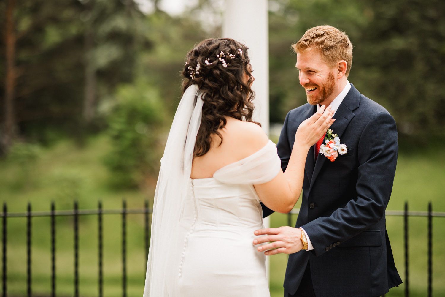 A tender wedding moment captured in front of an iron garden fence.