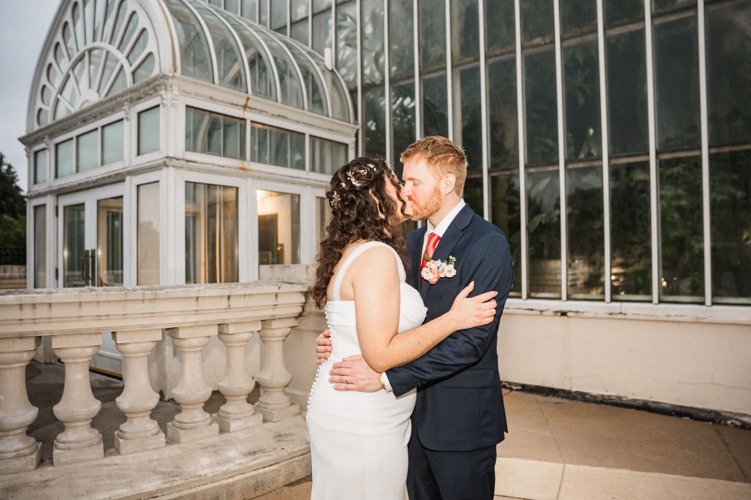 Newlyweds share an intimate moment outside a beautiful glass conservatory.
